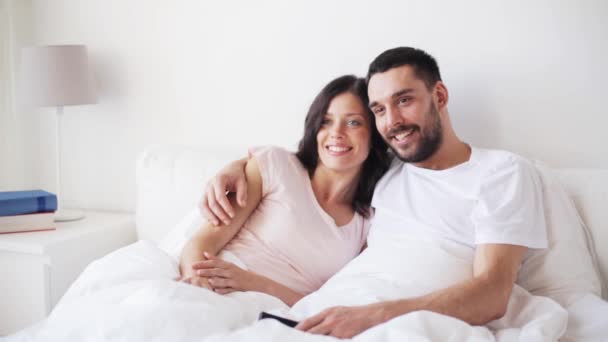 Feliz pareja viendo la televisión en la cama en casa — Vídeo de stock