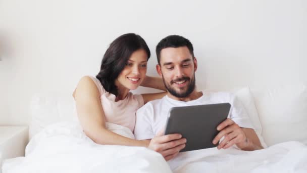 Casal sorridente na cama com computador tablet pc — Vídeo de Stock