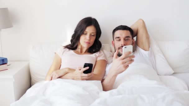 Happy couple with smartphones in bed — Stock Video