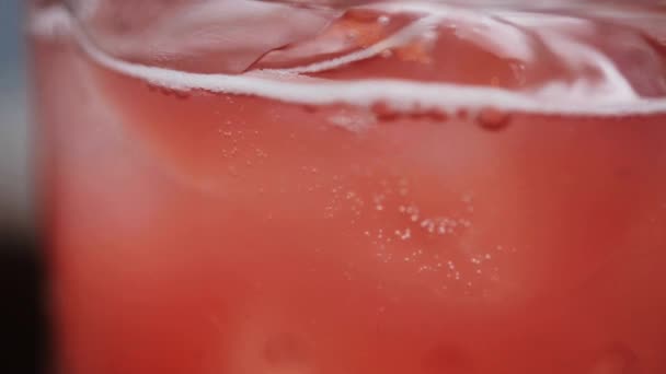 Розовый лимонад в стакане с кубиками льда — стоковое видео