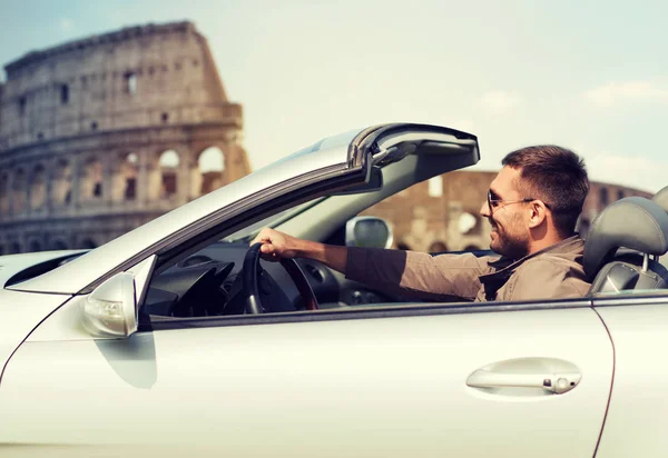 Homem feliz dirigindo carro cabriolet sobre coliseu — Fotografia de Stock