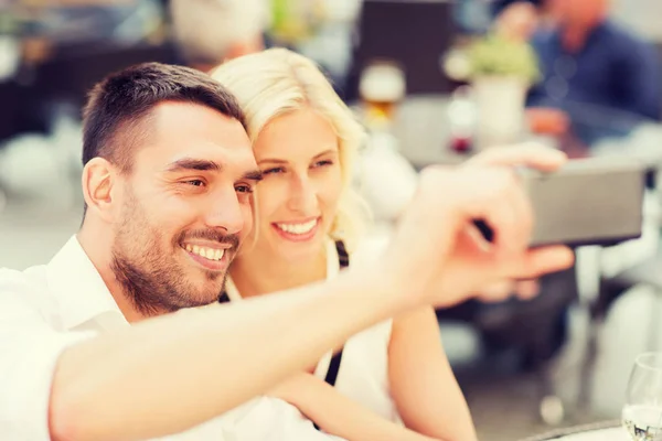 Счастливая пара делает селфи со смартфоном в кафе — стоковое фото