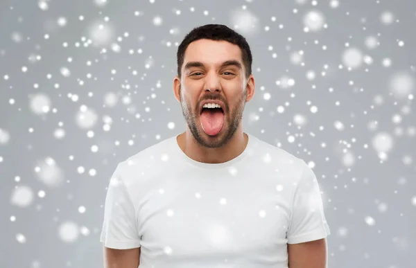 Homem mostrando sua língua sobre fundo de neve — Fotografia de Stock