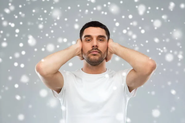 Joven cubriéndose las orejas con las manos sobre la nieve —  Fotos de Stock