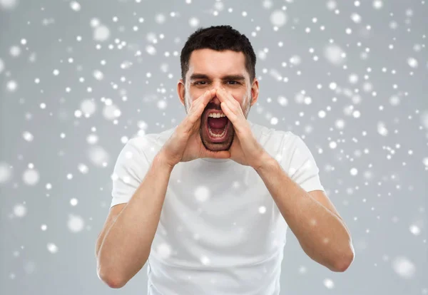 Сердитий крик людини в футболці над сніговим тлом — стокове фото