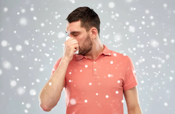 Больной человек с бумагой вытирает нос о снег — стоковое фото
