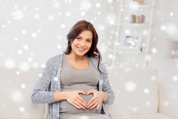 Šťastné těhotné ženě srdce gesto doma — Stock fotografie