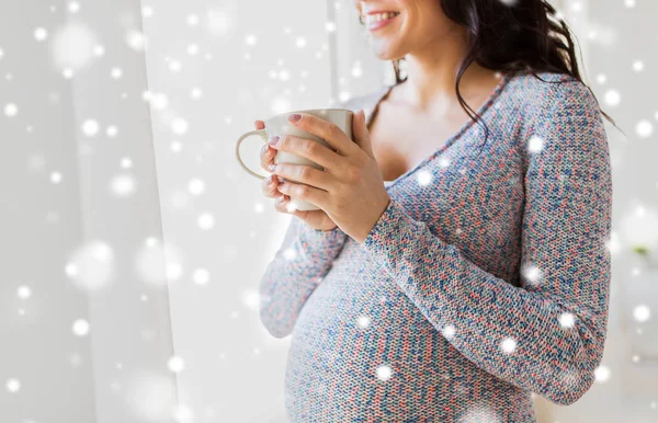 Close up van zwangere vrouw met thee kopje ter venster — Stockfoto