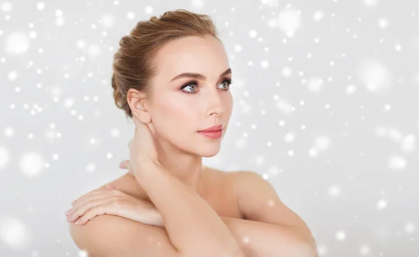 Mooie jonge vrouw gezicht en handen over sneeuw — Stockfoto