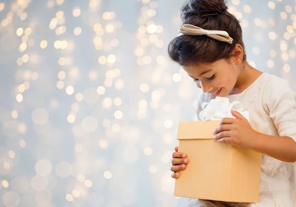 Petite fille souriante avec boîte cadeau sur les lumières — Photo