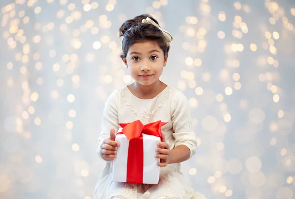 Petite fille souriante avec boîte cadeau sur les lumières — Photo