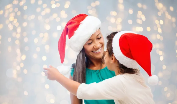 Happy mother and little girl in santa hats — Stock Photo, Image