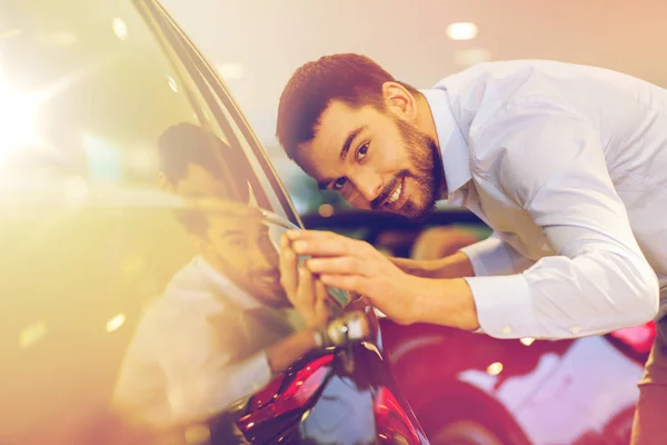 Счастливый человек трогает машину в автосалоне или салоне — стоковое фото