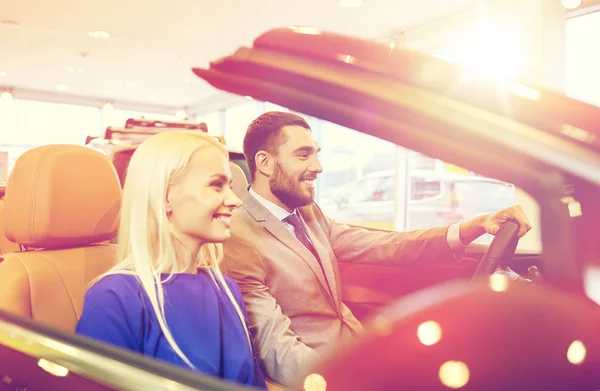 Happy couple sitting in car at auto show or salon — Stock Photo, Image