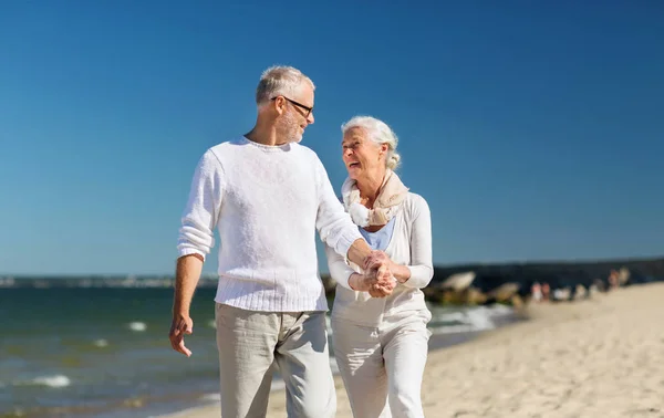 Happy senior couple holding hands on summer beach — Stock Photo, Image