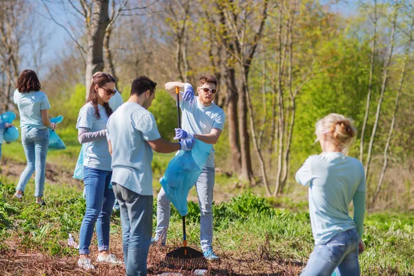 Voluntários com sacos de lixo área do parque de limpeza — Fotografia de Stock