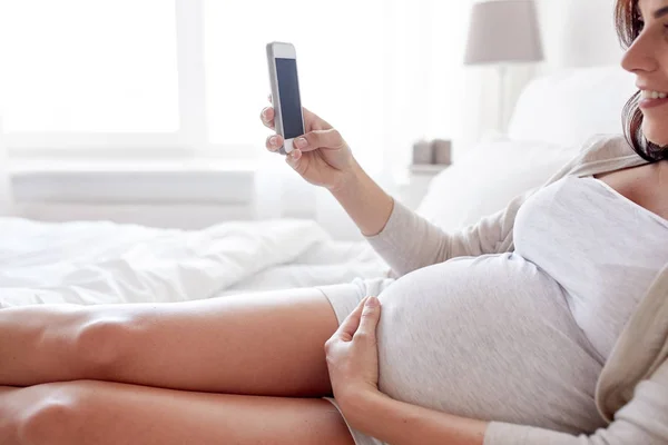 Nahaufnahme einer Schwangeren mit Smartphone im Bett — Stockfoto