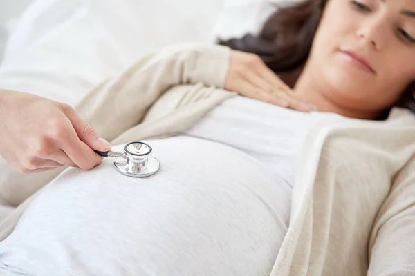 Médico con estetoscopio y mujer embarazada — Foto de Stock