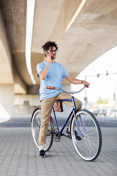 Hombre con teléfono inteligente y bicicleta de engranaje fijo en la calle — Foto de Stock