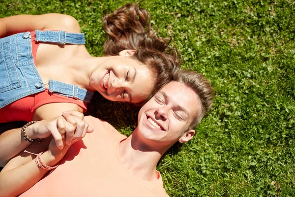 Happy teenage couple lying on grass at summer — Stock Photo, Image