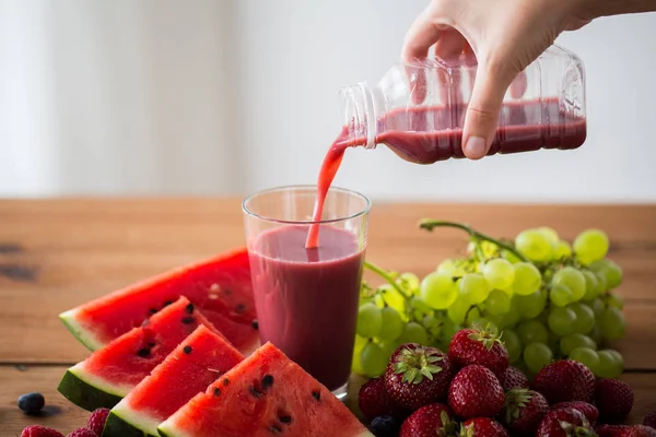 Wręczyć odlewania soku owocowego z butelki szklane — Zdjęcie stockowe