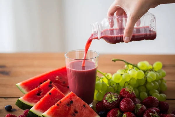 Mano verter zumo de fruta de la botella al vaso —  Fotos de Stock