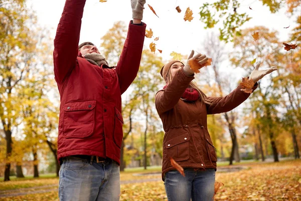 Glada unga par kasta hösten lämnar i park — Stockfoto