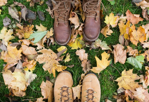 Paio di piedi in stivali e foglie di autunno — Foto Stock