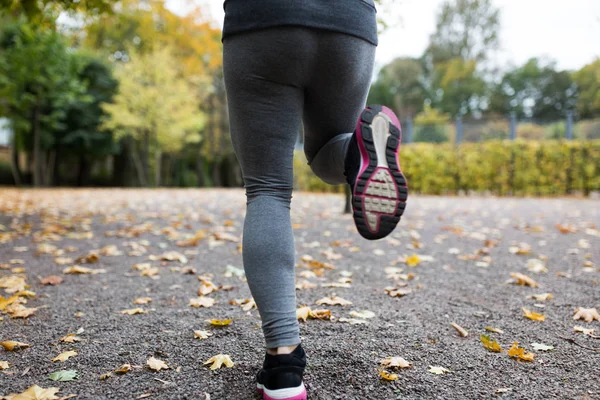 Close up of young woman running in autumn park — Stock Photo, Image