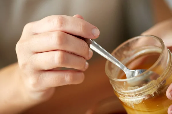 Närbild av kvinna händer med honung och sked — Stockfoto