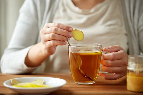 Nahaufnahme einer Frau, die Ingwer zum Tee mit Zitrone hinzufügt — Stockfoto