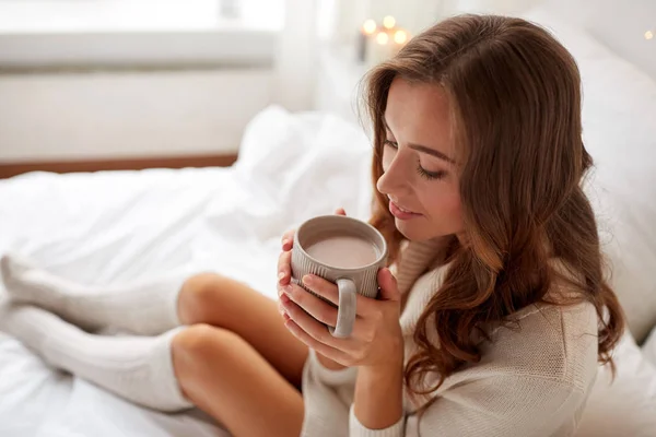 Щаслива жінка з чашкою какао в ліжку вдома — стокове фото