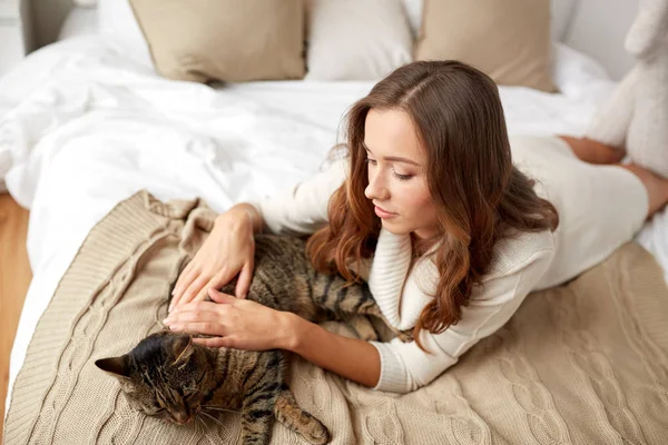 Mutlu genç kadın ile evde yatakta yatan kedi — Stok fotoğraf