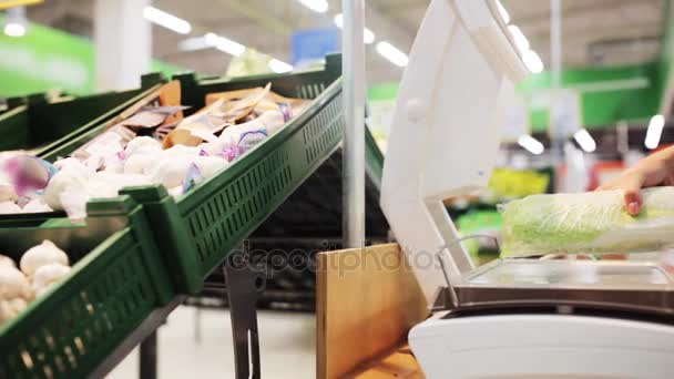 Vrouw met een gewicht van chinese kool op schaal bij supermarkt — Stockvideo