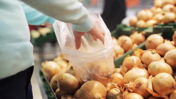 Mujer poniendo cebolla a la bolsa en la tienda de comestibles — Vídeo de stock