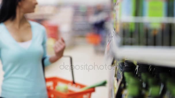 Жінка читає ярлик на пляшці оливкової олії в магазині — стокове відео