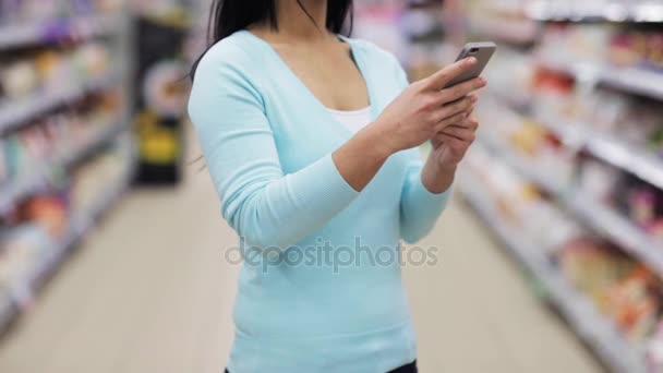 Женщина со смартфоном в супермаркете или магазине — стоковое видео
