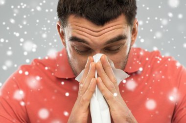 sick man with paper wipe blowing nose over snow clipart