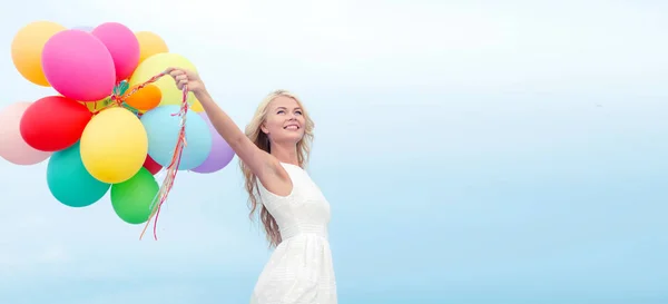 Улыбающаяся женщина с разноцветными воздушными шарами снаружи — стоковое фото