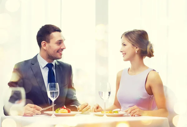 Sonriente pareja comiendo plato principal en restaurante —  Fotos de Stock