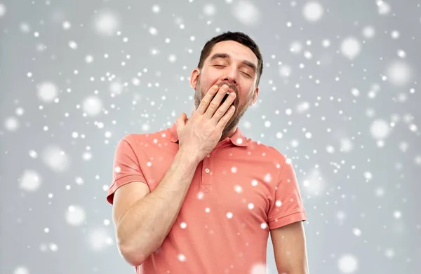 Cansado bocejo homem sobre neve fundo — Fotografia de Stock