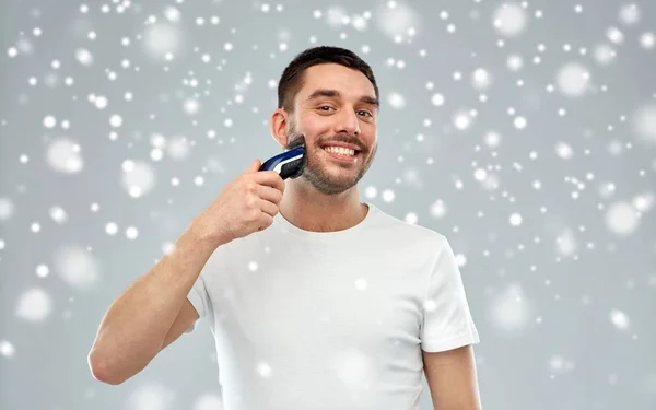 Uomo sorridente barba da barba con trimmer sulla neve — Foto Stock