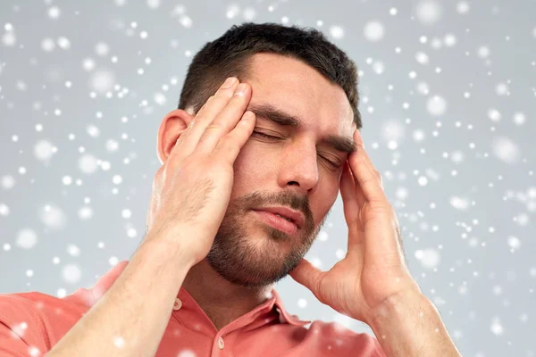 Homem infeliz que sofre de dor de cabeça sobre a neve — Fotografia de Stock