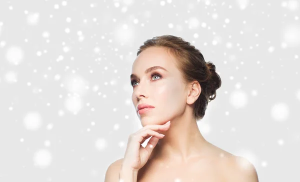 Mooie jonge vrouw haar gezicht aan te raken over sneeuw — Stockfoto