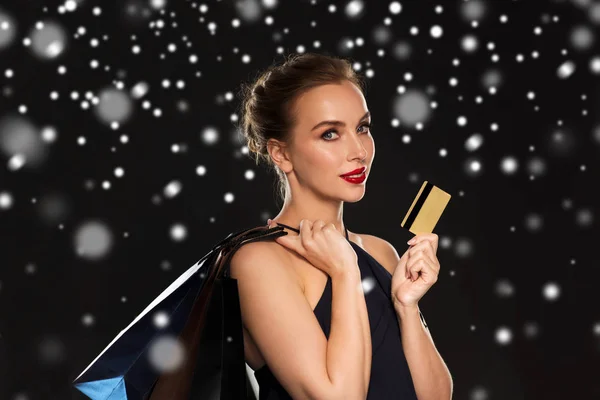 Vrouw met creditcard en boodschappentassen over sneeuw — Stockfoto