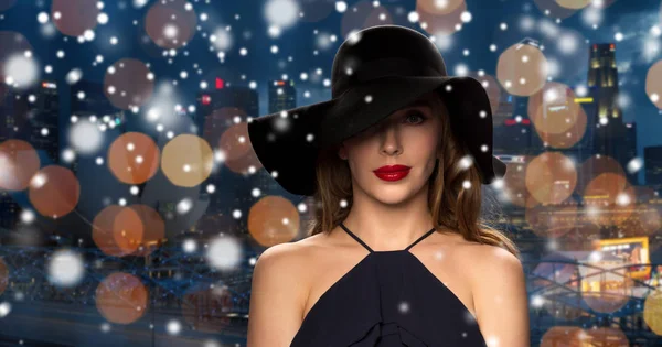 Bella donna in cappello nero sulla città di notte — Foto Stock