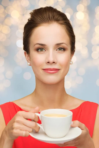 Vrouw in het rood met kop koffie over verlichting — Stockfoto