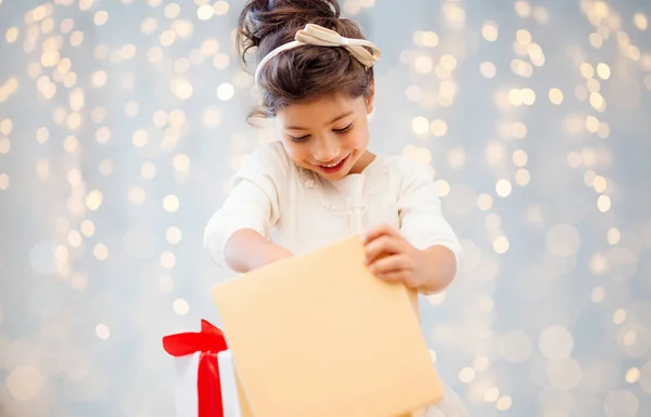 Sonriente niña abriendo caja de regalo sobre luces — Foto de Stock