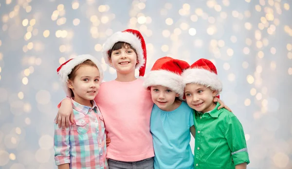 Gelukkig lieve kinderen in santa hoeden knuffelen — Stockfoto