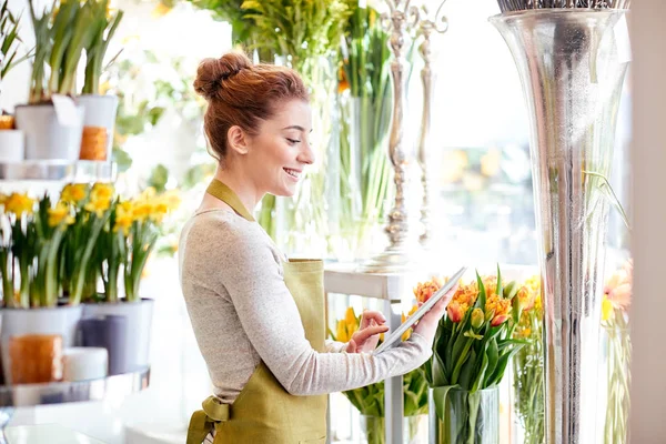 Mujer con la computadora de la tableta en la tienda de flores — Foto de Stock